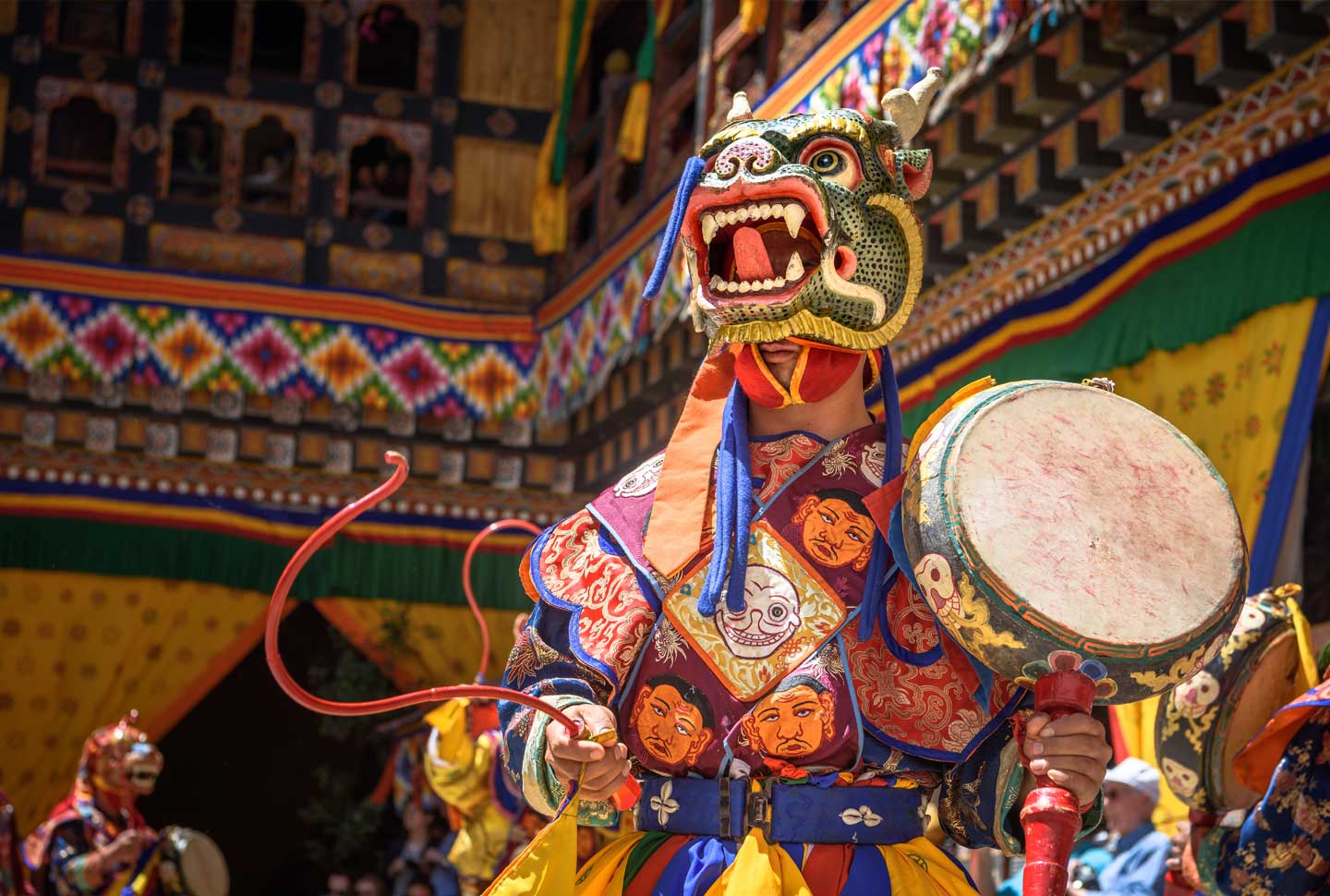 Monk playing the drums and dacing at colorful mask dance at yearly Paro Tsechu festival in Bhutan